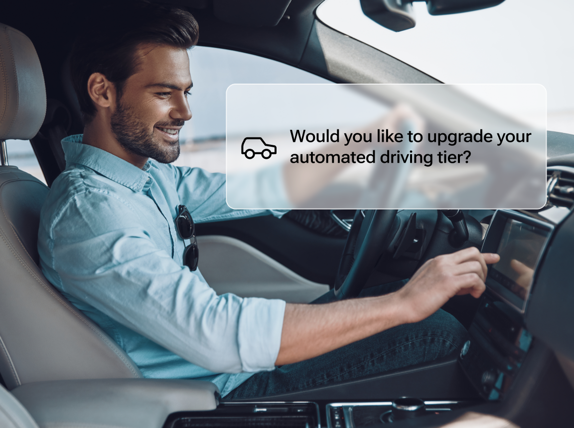 A side view of a man driving a car, with a notification that says: “Would you like to upgrade your automated driving tier?”